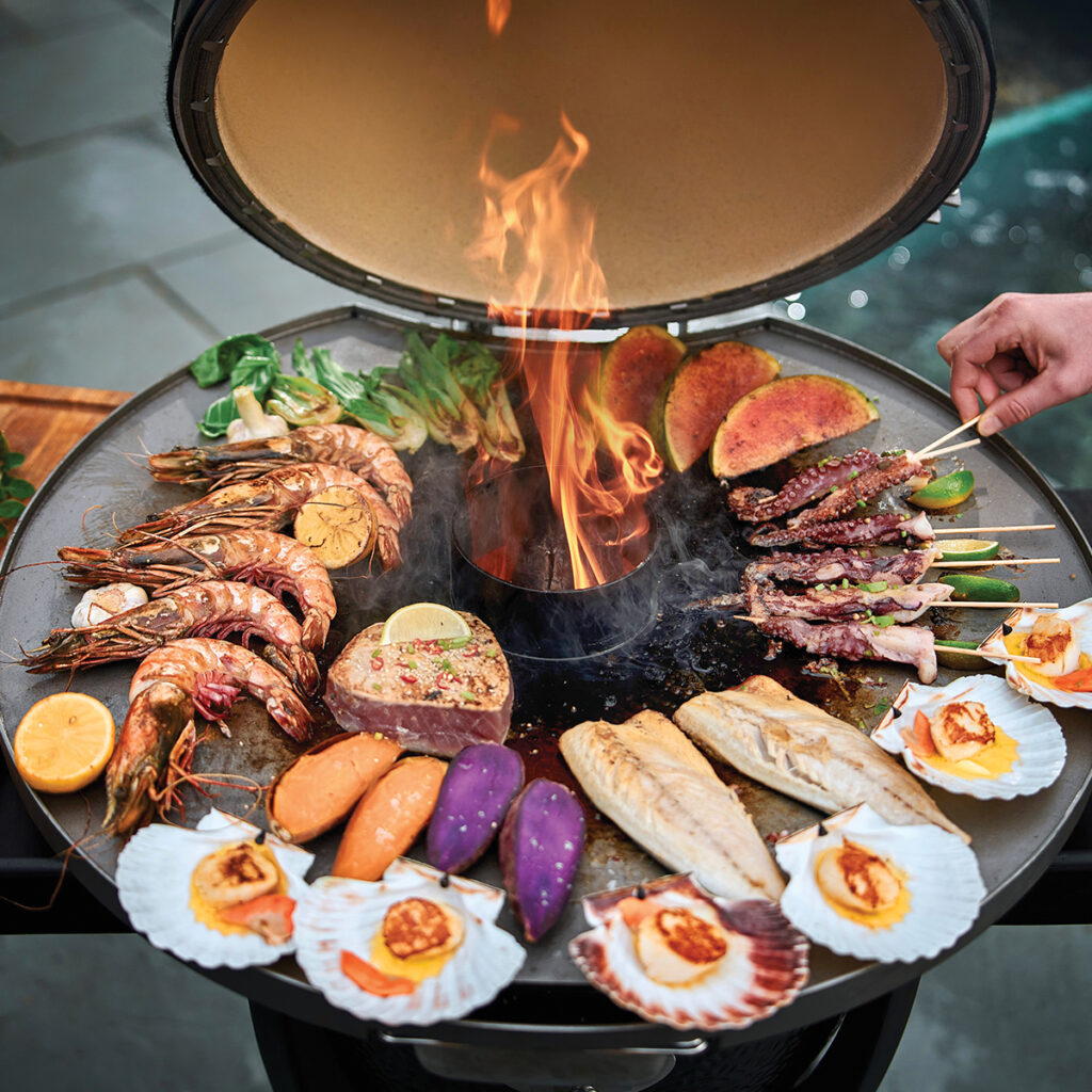 Matt Tebbutt takes over the fireplate with a sweeping seafood spread — sesame-crusted tuna, soy-glazed octopus skewers, yuzu butter scallops, grilled prawns, and crispy-skinned mackerel all cooking at once across the heat zones. It's a masterclass in live-fire timing, finished with charred watermelon and caramelised sweet potato for a feast that's as spectacular to watch as it is to eat.